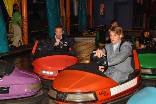 Dr. House and Dr. Chase in seperete red bumper cars whilst dressed up in suits in the middle of bumping into eachother.