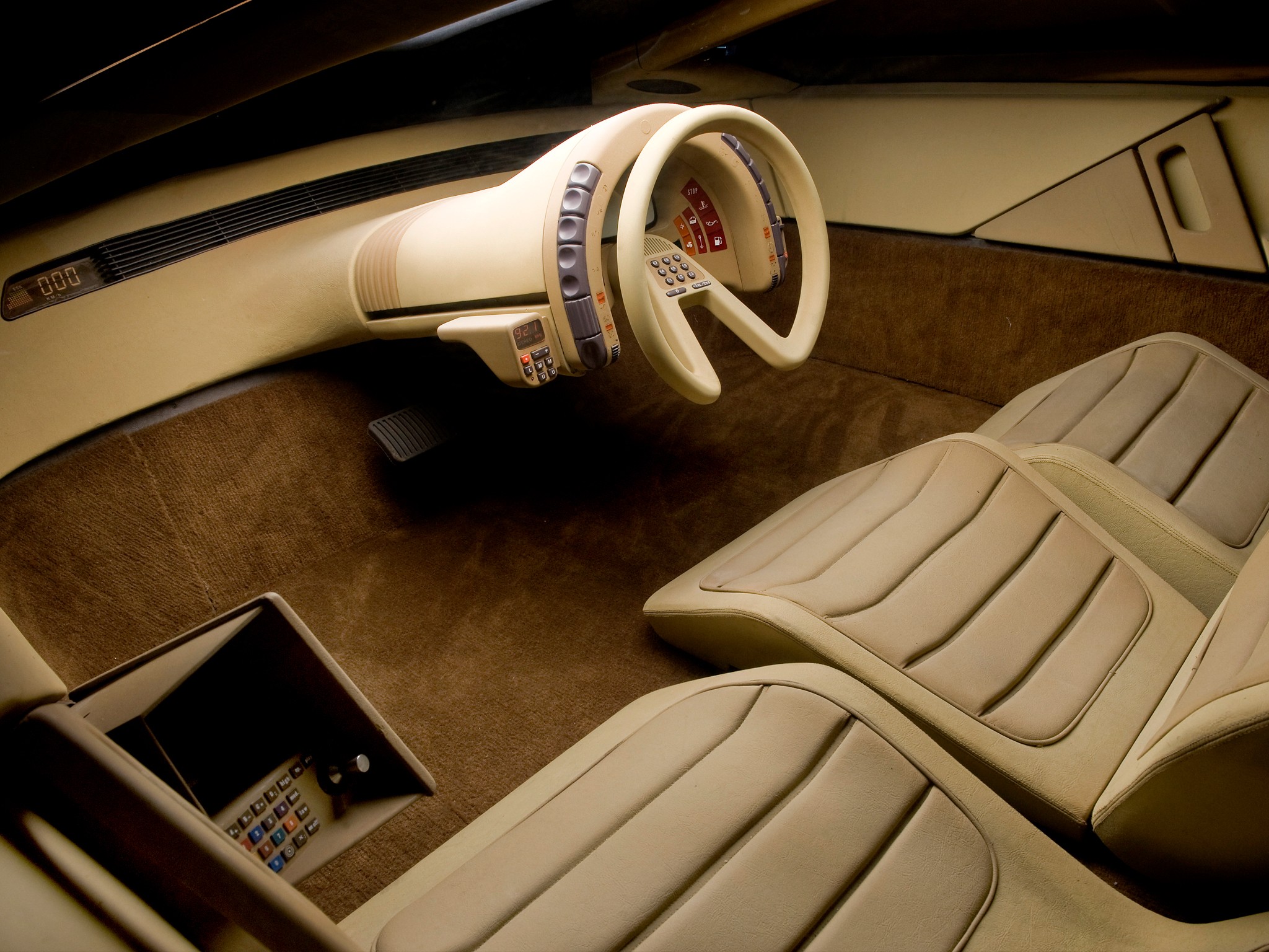 A photo of the interior, where the all the console buttons are clustered on the frame around the steering wheel and the steering wheel is shaped like a pie with and missing piece on the bottom