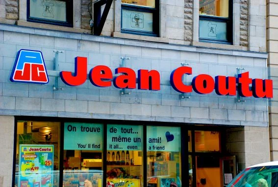 Picture of a Jean-Coutu pharmacy’s storefront. In the windows, the slogan in English reads: "You’ll find it all… Even a friend!"