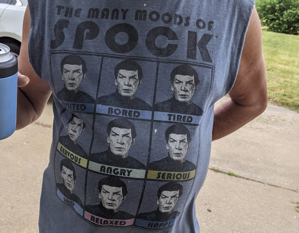 T-shirt 'Many moods of Spock' with 9 duplicate pics of spock listing different moods; excited, angry, sad, etc. text; >THE MANY MOODS OF SPOCK EXCITED BORED TIRED NERVOUS ANGRY SERIOUS SAD RELAXED HAPPY