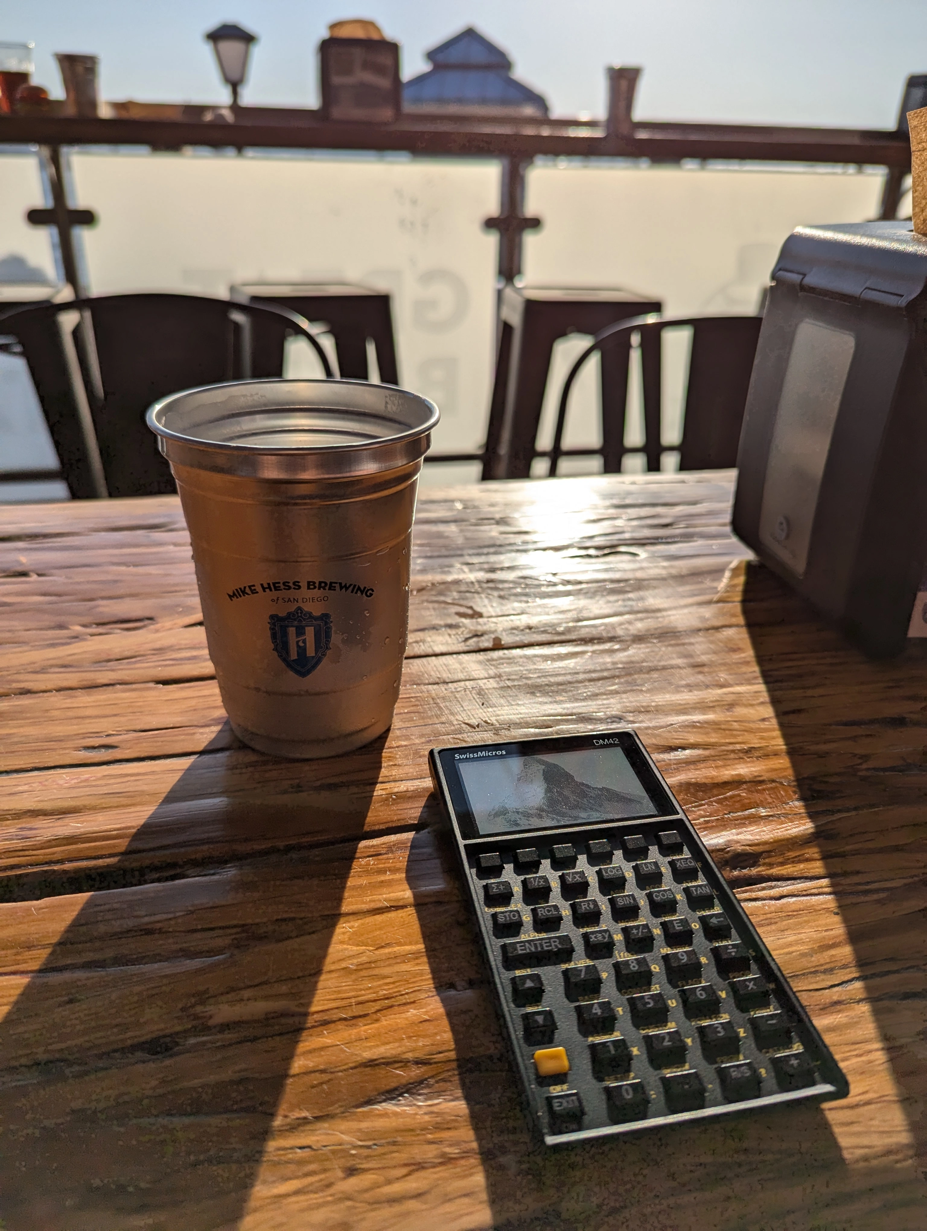 A Swissmicros DM42 sat on a table in the sun next to a beer.